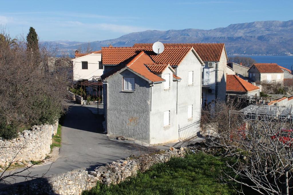 una pequeña casa blanca con techos rojos en una colina en Apartments with a parking space Supetar, Brac - 6036, en Supetar
