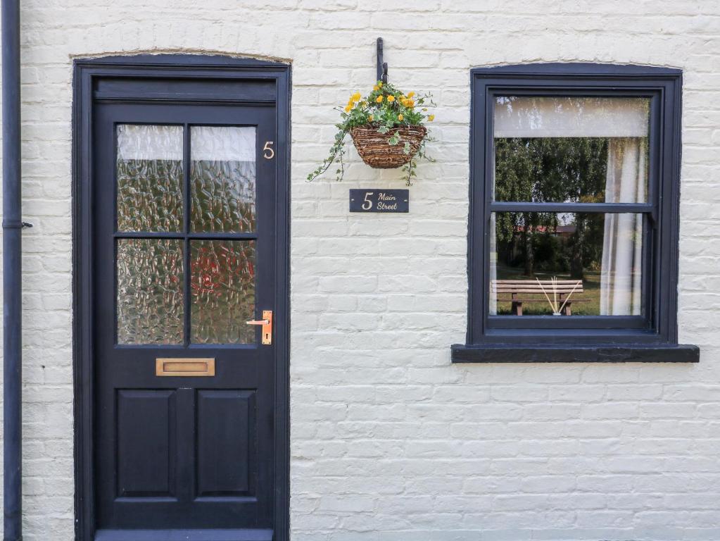 uma porta preta e janelas num edifício de tijolos brancos em No 5 Main Street em Hull