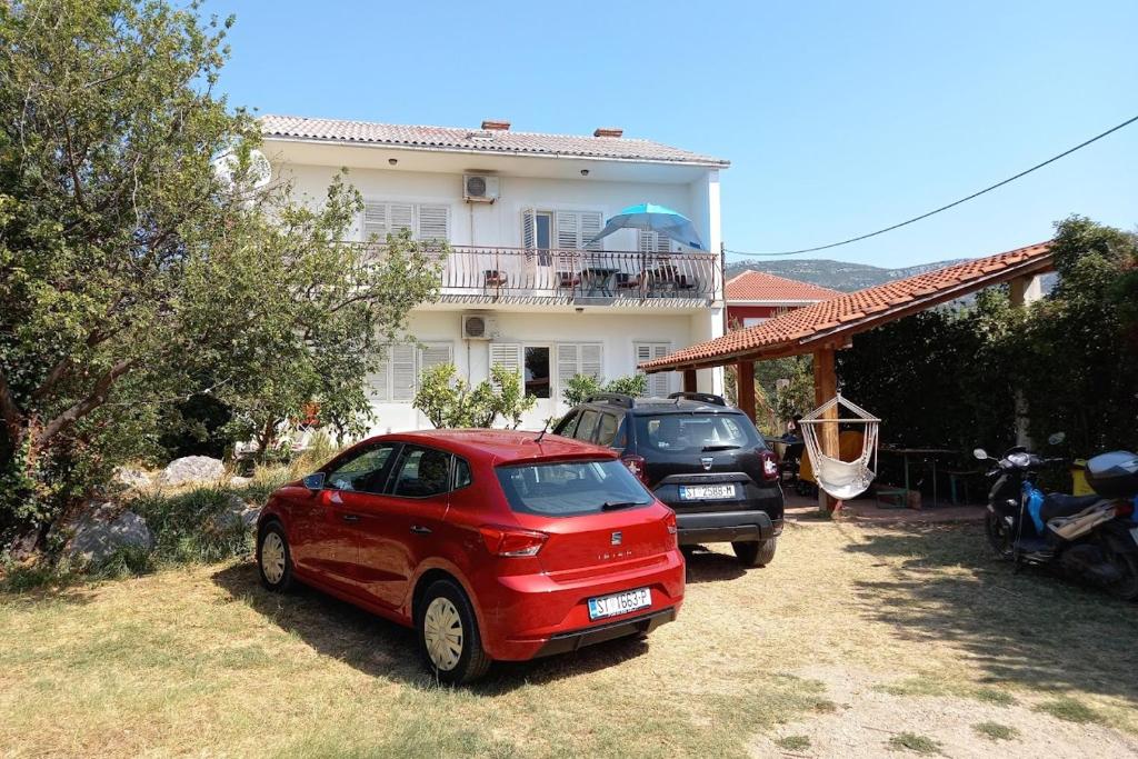 una macchina rossa parcheggiata di fronte a una casa di Apartments by the sea Kastel Stari, Kastela - 6059 a Kaštela (Castelli)
