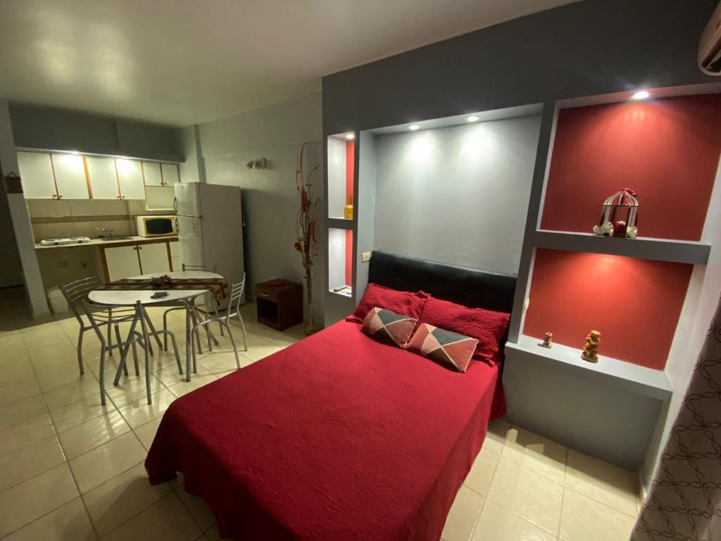 1 dormitorio con cama roja y cocina en MONOAMBIENTE CENTRICO AMOBLADO, en San Juan