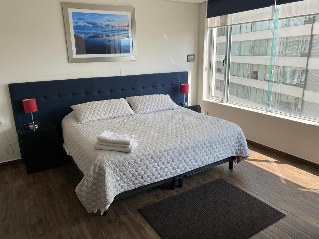 a bedroom with a bed with a blue headboard and a window at Napoles Suites in Mexico City