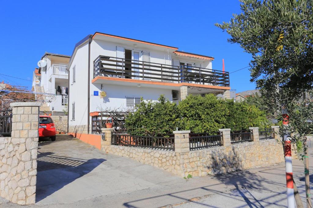 une maison blanche avec une clôture devant elle dans l'établissement Apartments by the sea Seget Vranjica, Trogir - 6094, à Seget Vranjica