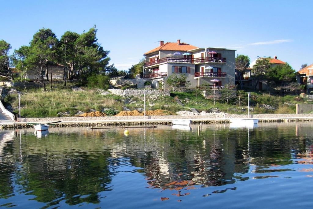 uma casa numa colina ao lado de um corpo de água em Seaside apartments with a swimming pool Nin, Zadar - 6153 em Nin