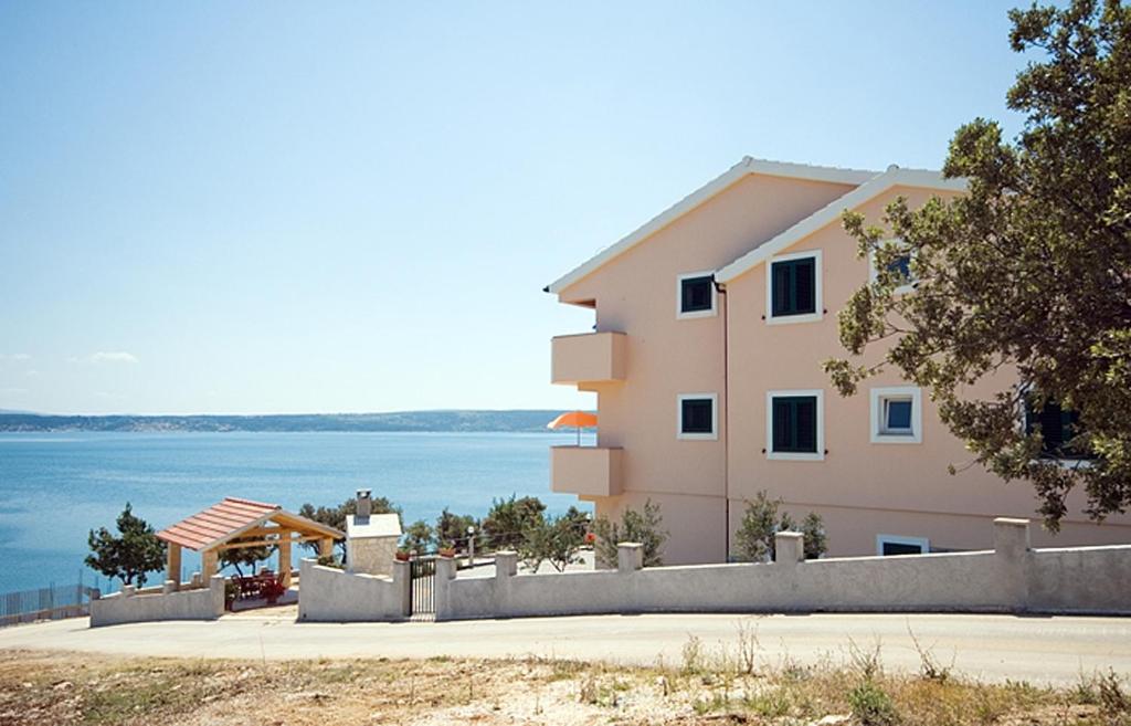 een roze gebouw met uitzicht op het water bij Seaside apartments with a swimming pool Posedarje, Novigrad - 6162 in Posedarje