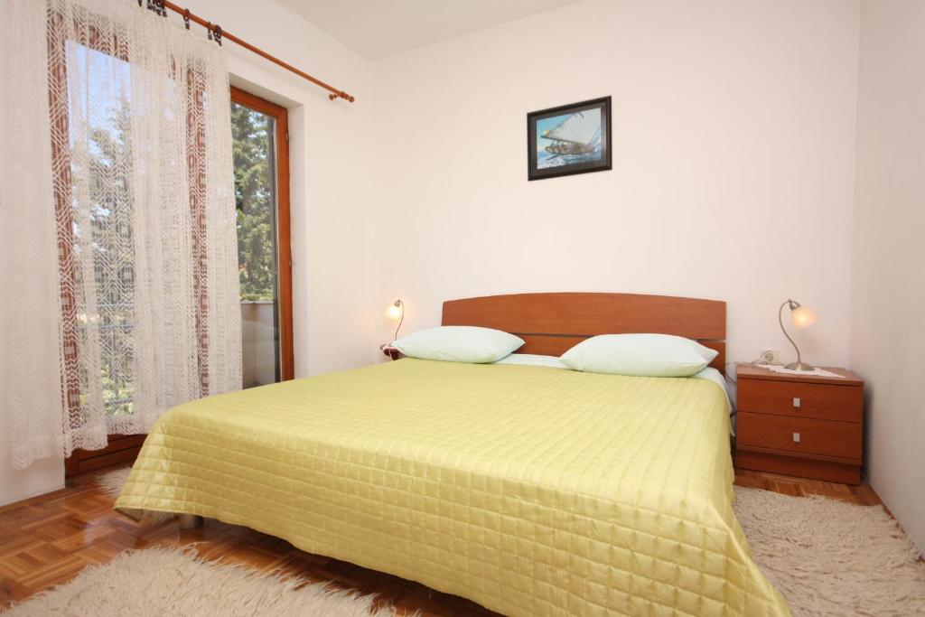 a bedroom with a bed with a yellow bedspread and a window at Apartments with parking space Turanj, Biograd - 6212 in Turanj