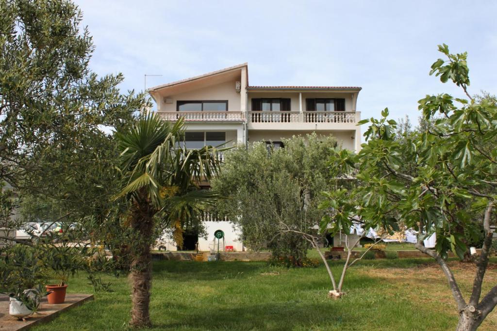 a house in the middle of a yard with trees at Apartments and rooms by the sea Vodice - 6182 in Vodice