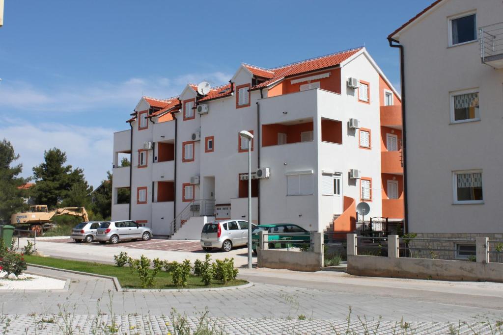 a building with cars parked in a parking lot at Apartments with a parking space Vodice - 6183 in Vodice