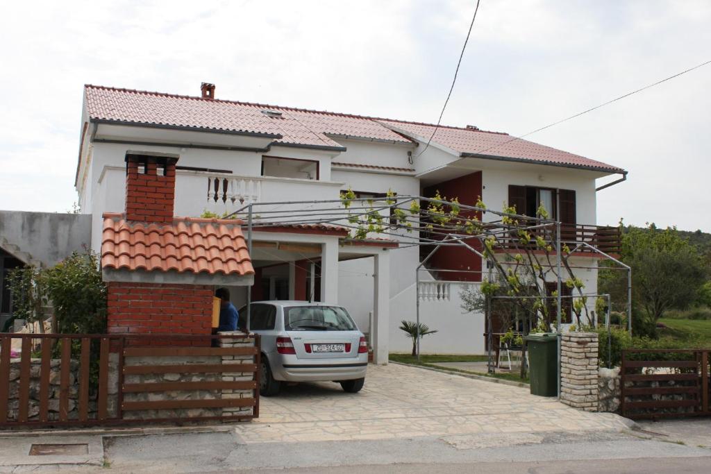 una casa blanca con un coche aparcado en la entrada en Apartments with a parking space Ljubac, Zadar - 6141, en Ražanac