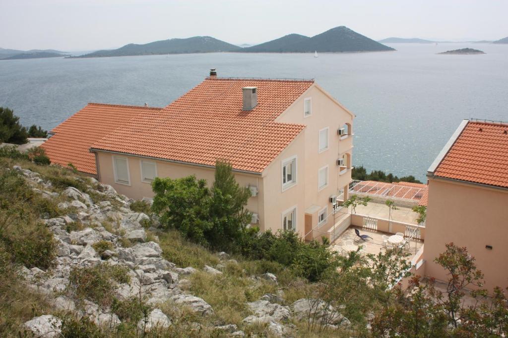 ein Haus auf einem Hügel neben dem Wasser in der Unterkunft Apartments by the sea Drage, Biograd - 6171 in Drage