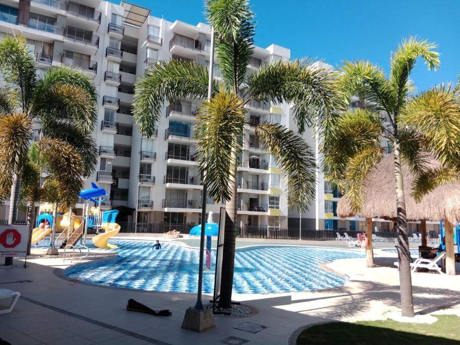a swimming pool with palm trees in front of a building at Apartamento para tu descanso piso 7 in Ricaurte