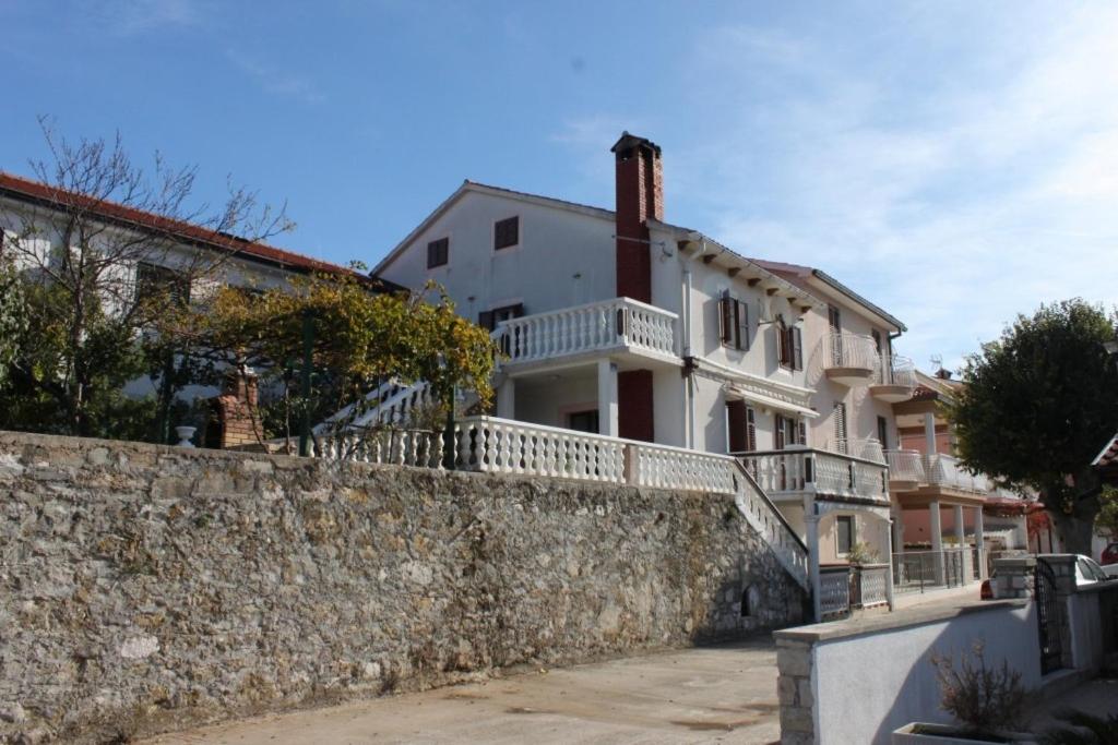 a large white house behind a stone wall at Apartments by the sea Duga Luka - Prtlog, Labin - 7491 in Labin