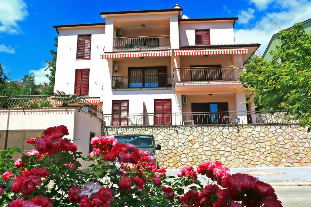 a building with red flowers in front of it at Apartment Rabac 7429a in Rabac