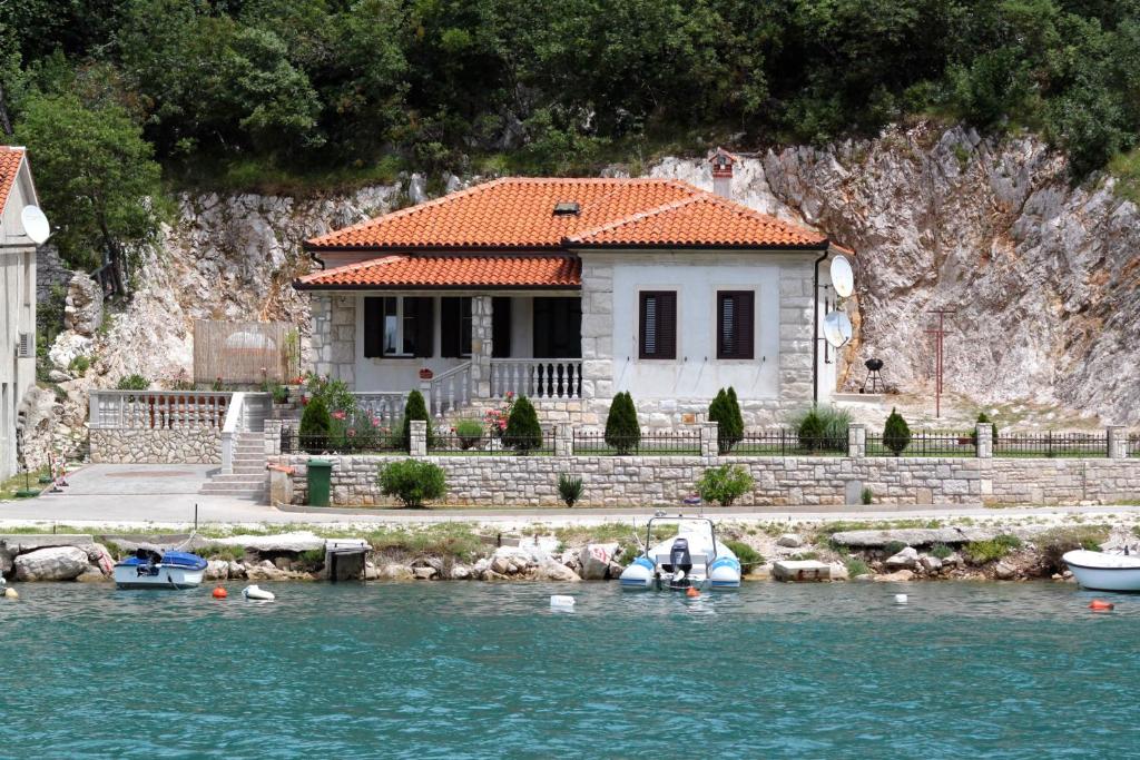 a house on the water with boats in front of it at Seaside holiday house Plomin Luka, Labin - 7466 in Plomin