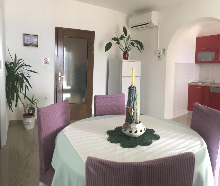 a table with purple chairs and a candle on it at Apartments with a parking space Rabac, Labin - 7442 in Rabac