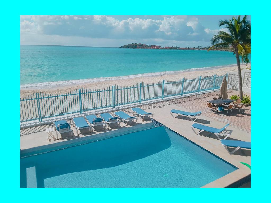 a swimming pool with chairs and a beach at Villas on Great Bay VILLA FOXIE in Philipsburg