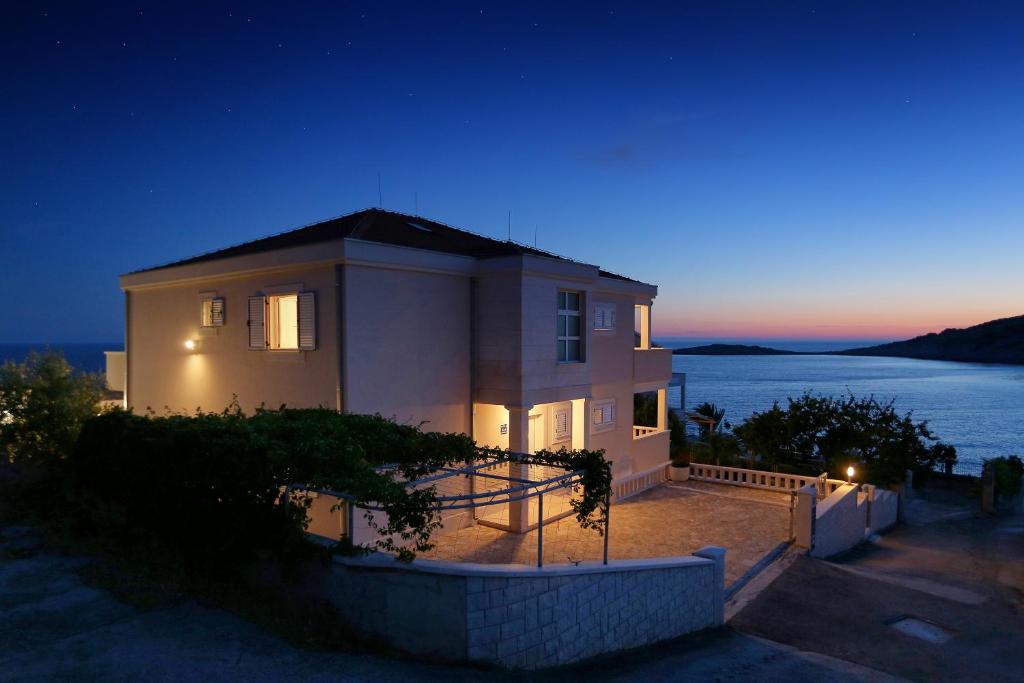 a house with a view of the ocean at night at Apartments by the sea Razanj, Rogoznica - 7484 in Ražanj