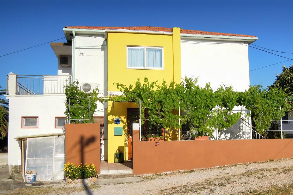 a yellow and white house with a fence at Apartments by the sea Slatine, Ciovo - 7544 in Slatine