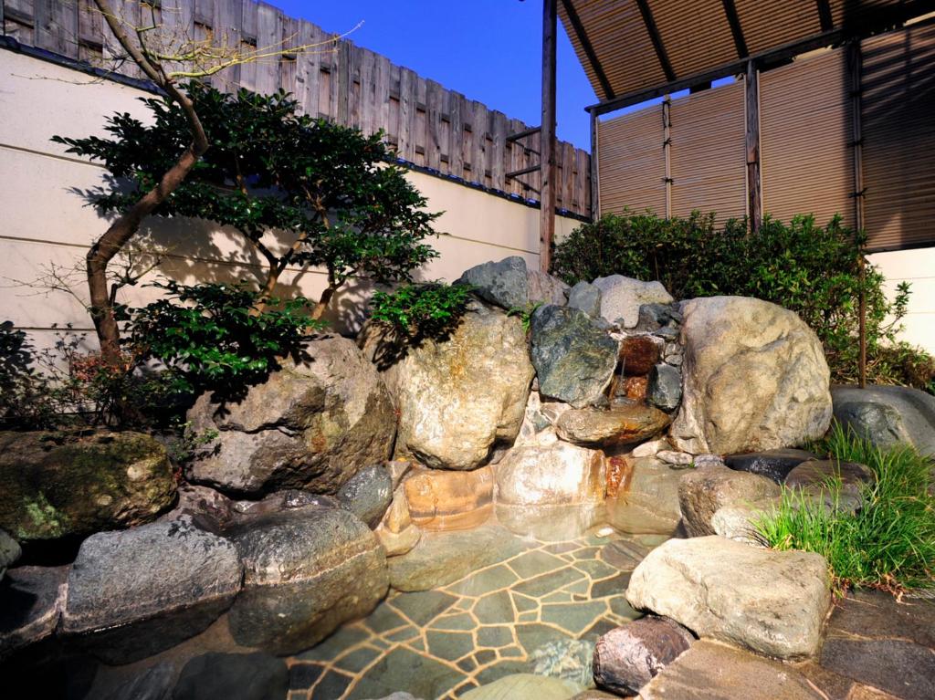a garden with rocks and a pond in front of a building at Hotel Hagoromo in Shizuoka