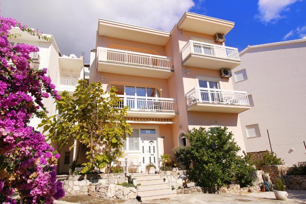 a large apartment building with balconies and purple flowers at Apartments by the sea Duce, Omis - 7576 in Duće