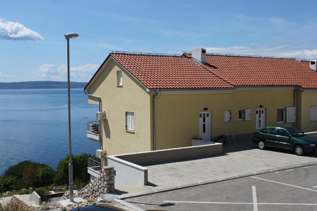 a yellow building with a parking lot next to the water at Apartments with a parking space Novi Vinodolski - 7503 in Novi Vinodolski