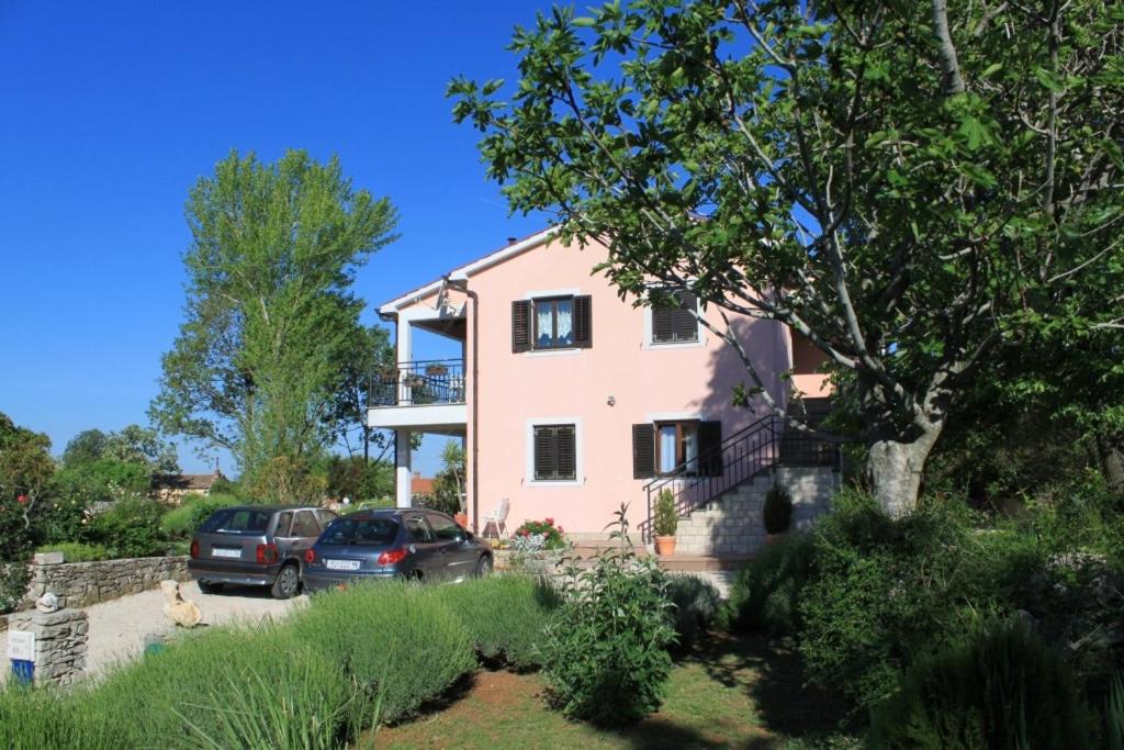 a pink house with two cars parked in the driveway at Apartments with a parking space Presika, Labin - 7617 in Labin