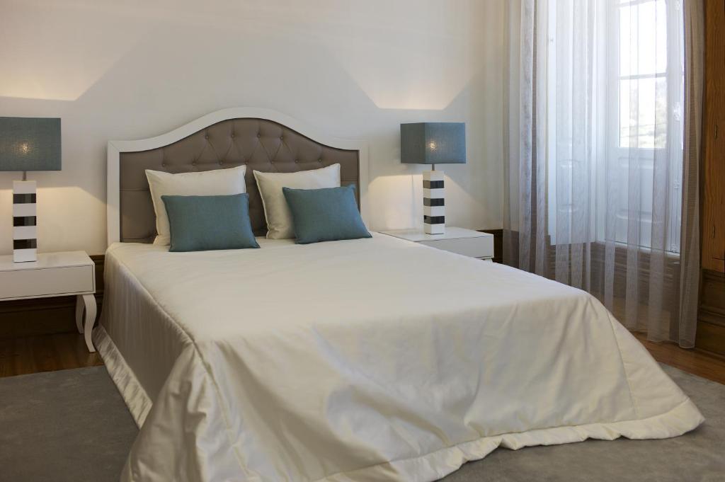 a bedroom with a large white bed with blue pillows at Casa de Cambres in Lamego