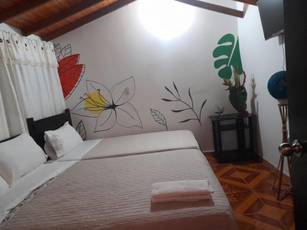 a bedroom with a bed with a flower mural on the wall at La Cabaña Eco Hotel in Suaita