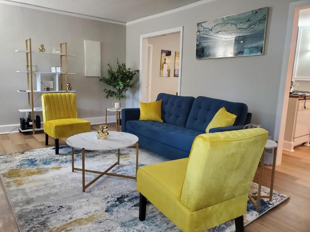 a living room with a blue couch and two yellow chairs at Cheerful 2 BR Near Colleges, Downtown, Attractions in Montgomery