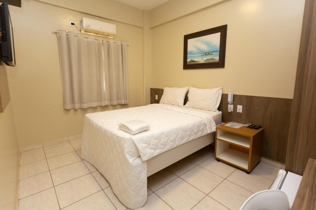 Un pequeño dormitorio con una cama blanca y una mesa en HOTEL EXECUTIVO, en Parauapebas