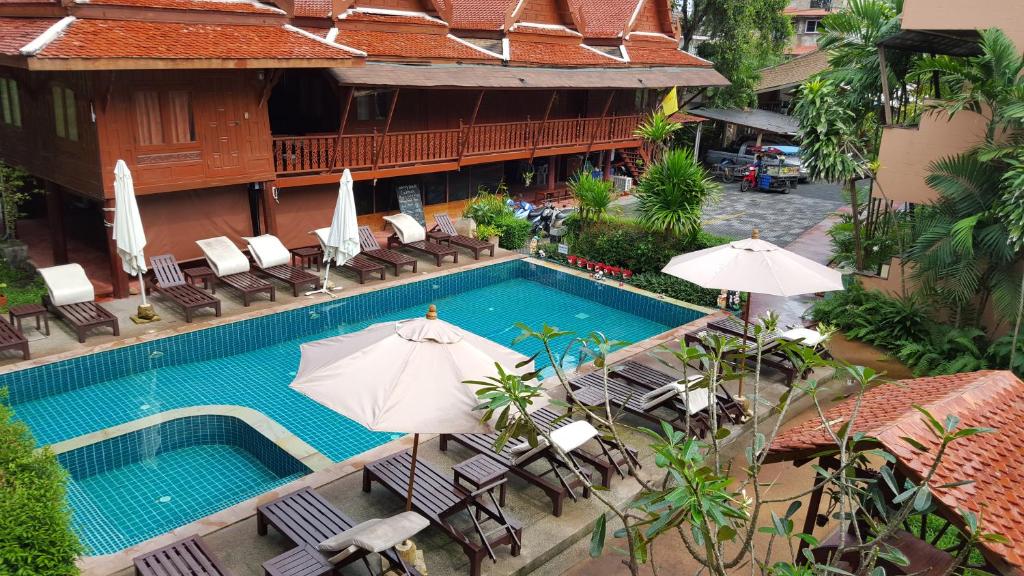 - une vue sur la piscine bordée de chaises et de parasols dans l'établissement Grand Thai House Resort, à Lamai