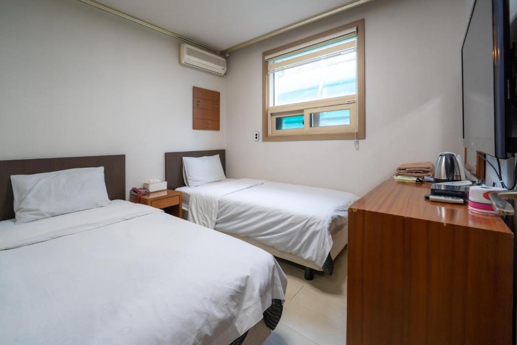 Habitación con 2 camas, escritorio y ventana. en Amiga Inn Seoul Hotel en Seúl