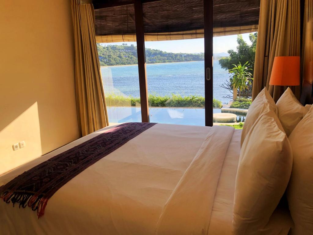 a bedroom with a bed with a view of the ocean at Lombok Sunset Bay Resort in Sekotong