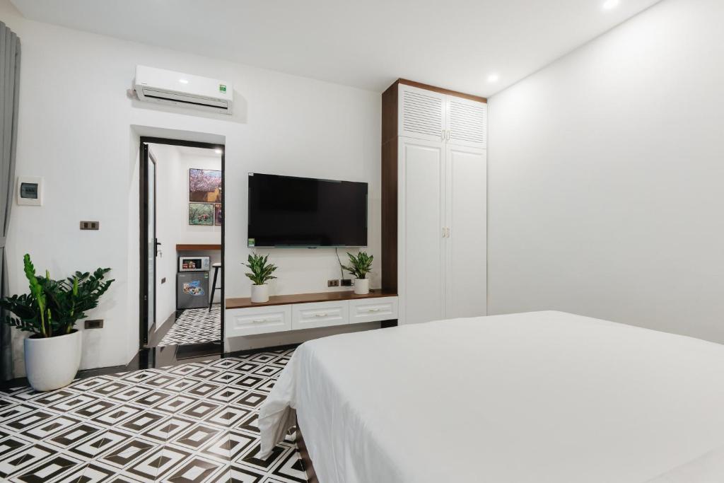 a white bedroom with a bed and a flat screen tv at Hanoi Old Quarter in Hanoi