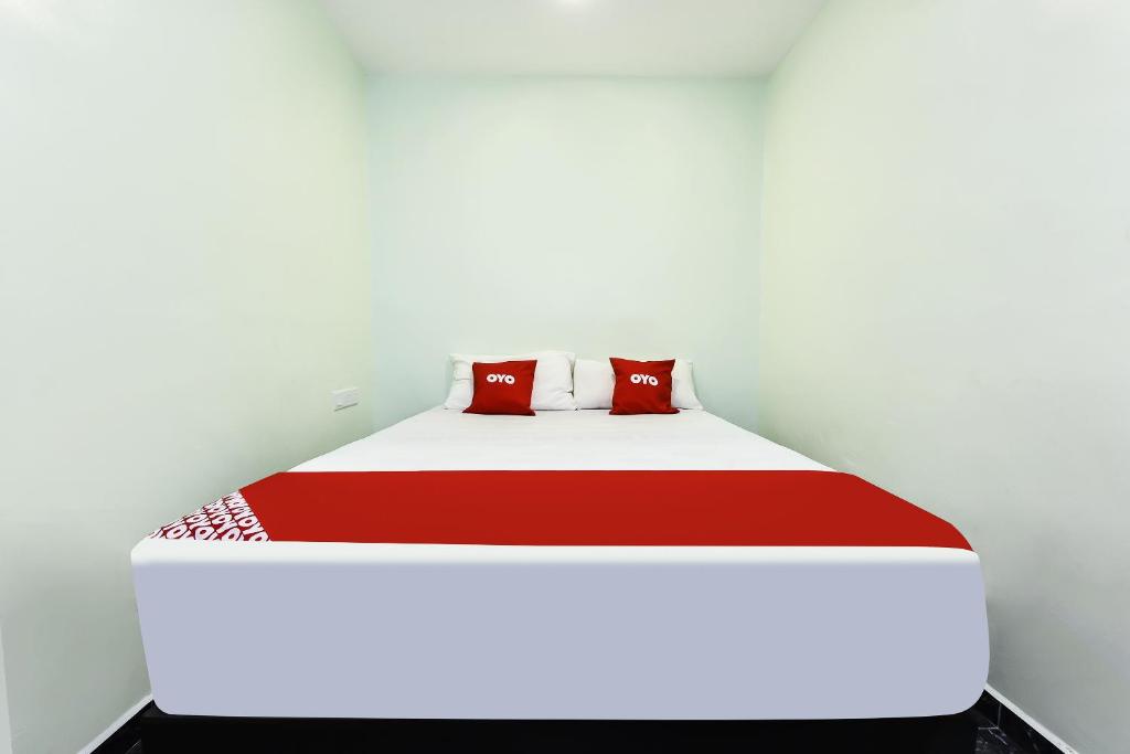 a bed with red and white sheets and pillows at OYO 90445 Th Hotel in Bahau