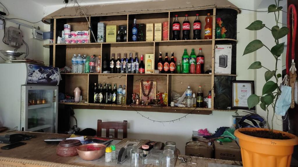 una mensola piena di bottiglie su un muro di Hotel small town guest house a Bandipur