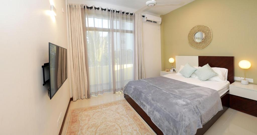 a bedroom with a bed and a television and a window at ARON'S Lavinia RUBY in Mount Lavinia