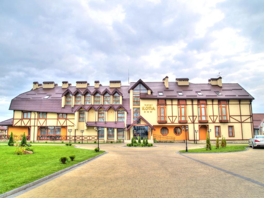 un gran edificio con un césped verde delante de él en Hotel Kopa - Lviv, en Leópolis