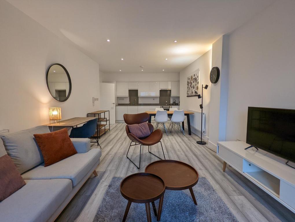 a living room with a couch and a tv at Hounslow Apartments by Charles Hope in Hounslow