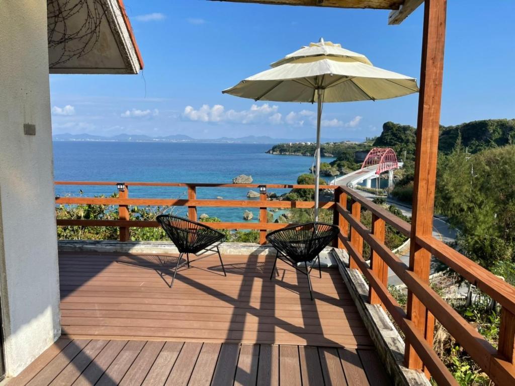 een houten terras met 2 stoelen en een parasol bij Pension Takahanari - Vacation STAY 06502v in Uruma