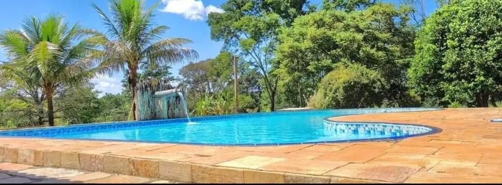 a swimming pool in a yard with trees at Hotel Fazenda Serra da Irara in Corumbá de Goiás