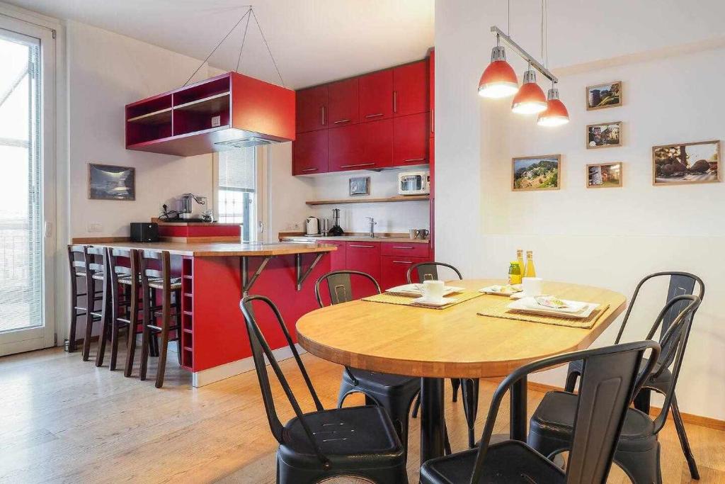 a kitchen with red cabinets and a wooden table and chairs at UCA14 Luxury large apartment with private terrace in Citylife in Milan