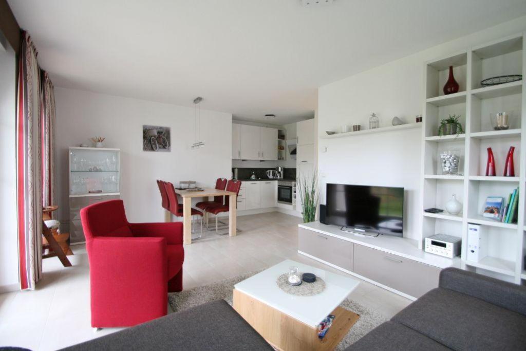 a living room with a red chair and a television at Villa Brigitte App 01 - Arielle in Nienhagen