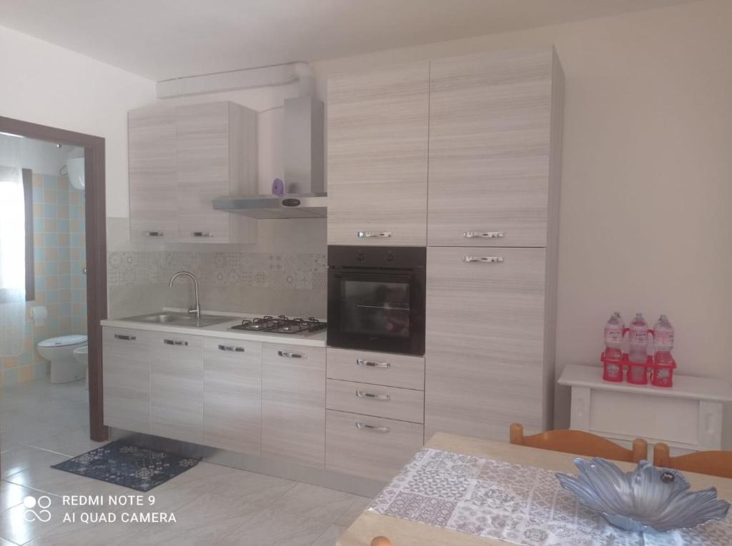 Una cocina con gabinetes blancos y un horno de estufa. en Tortolì-Porto Frailis-Arbatax, en Àrbatax