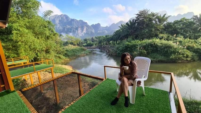 una mujer sentada en una silla junto a un río en Phu Siab Mhok@KhaoSok en Khao Sok