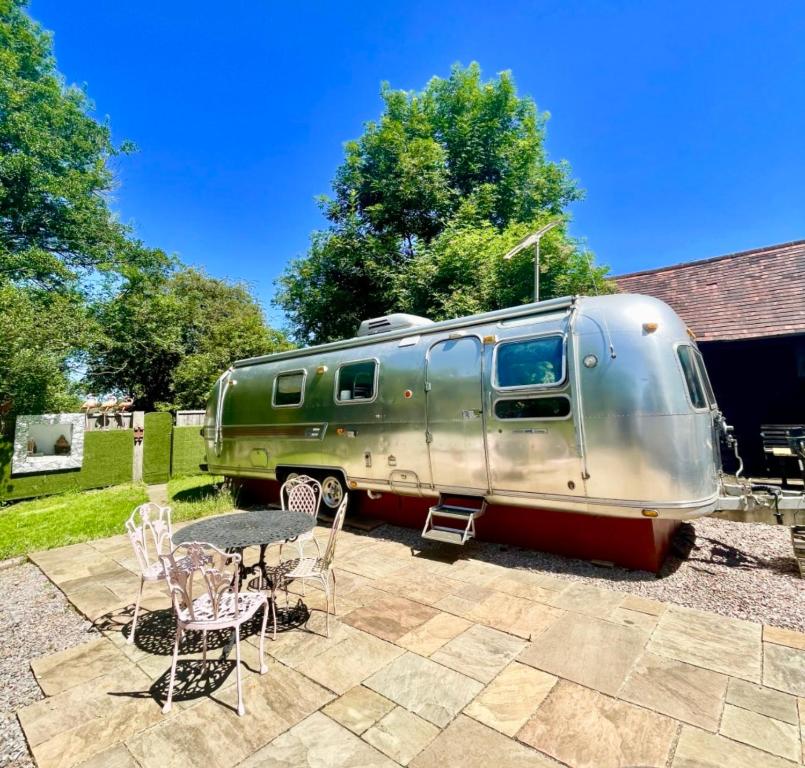 un remolque estacionado en un patio con mesa y sillas en Airstream at Hardham West Sussex Sleeps 4 en Pulborough