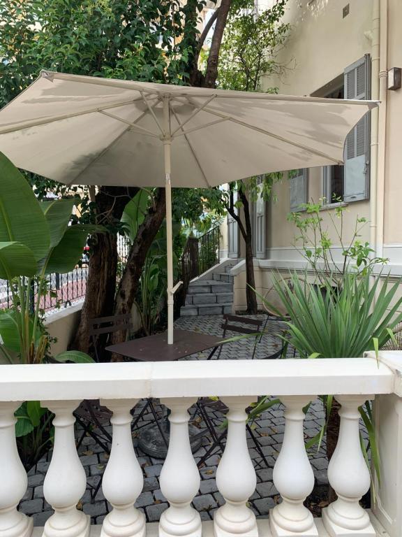 einen weißen Tisch mit Sonnenschirm auf der Veranda in der Unterkunft Villa Les Fougeres 2p jardin parking in Cannes