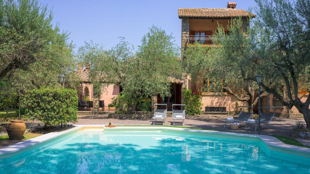 una piscina con 2 sillas frente a una casa en Villa Sylva 6&2, Emma Villas, en Frattocchie