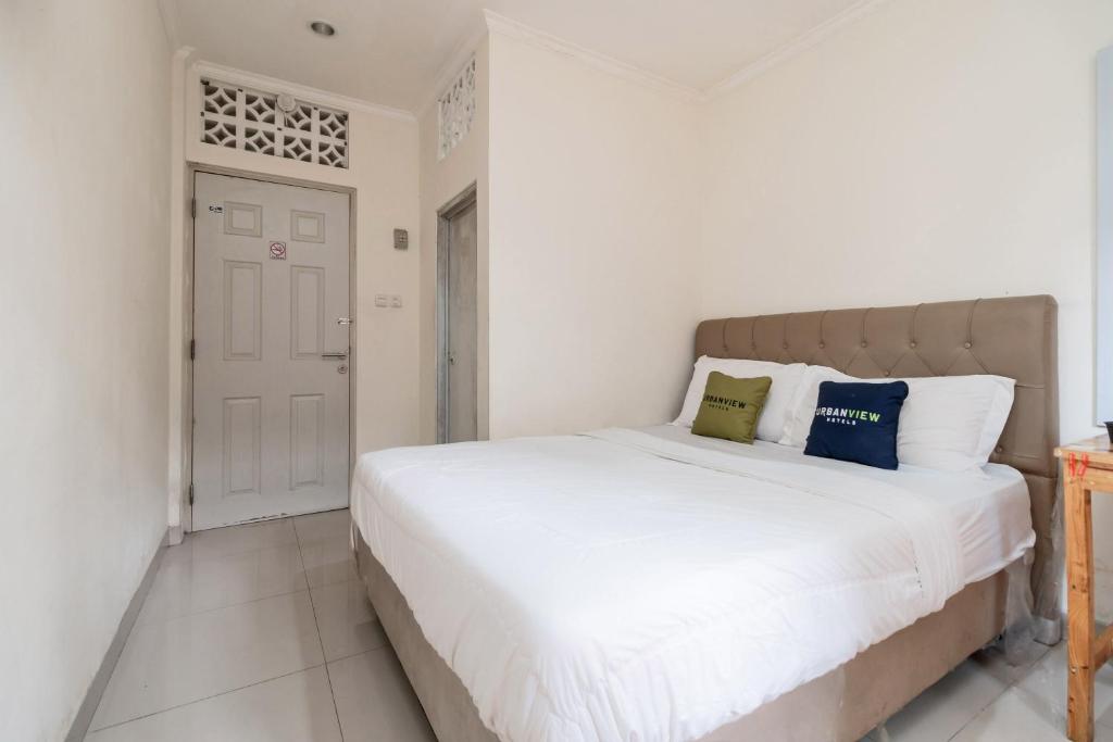 a bedroom with a large white bed with blue pillows at Urbanview Hotel Minongga Pondok Labu by RedDoorz in Jakarta
