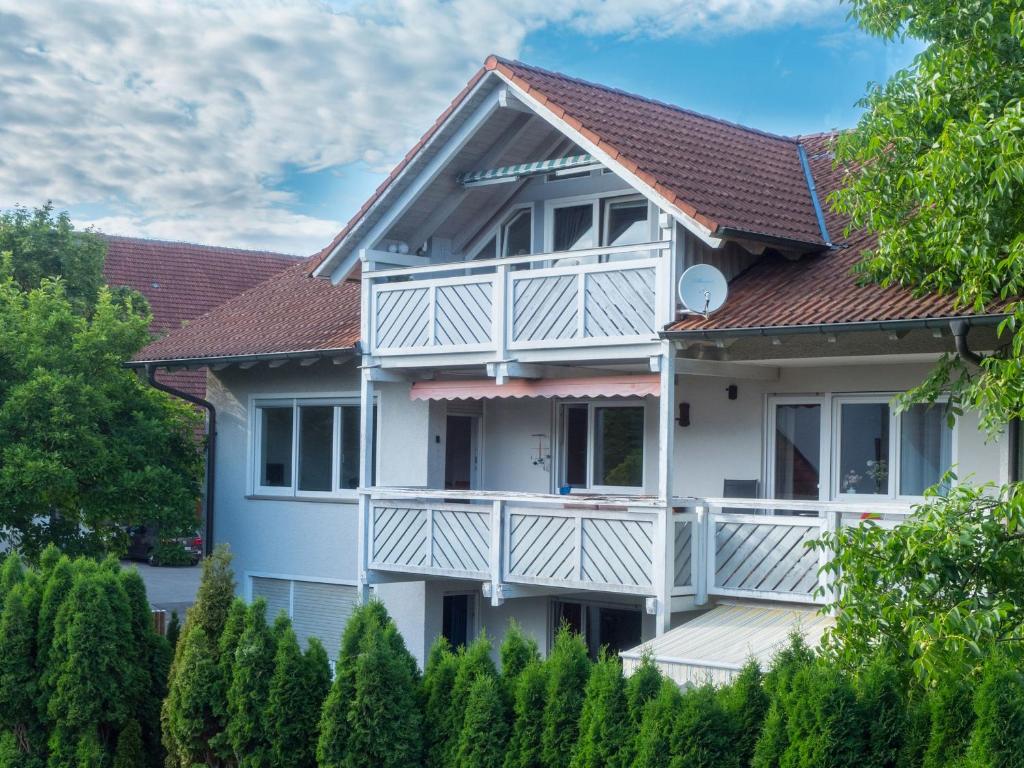 una casa bianca con balcone e alberi di Ferienwohnung Denn a Langenargen