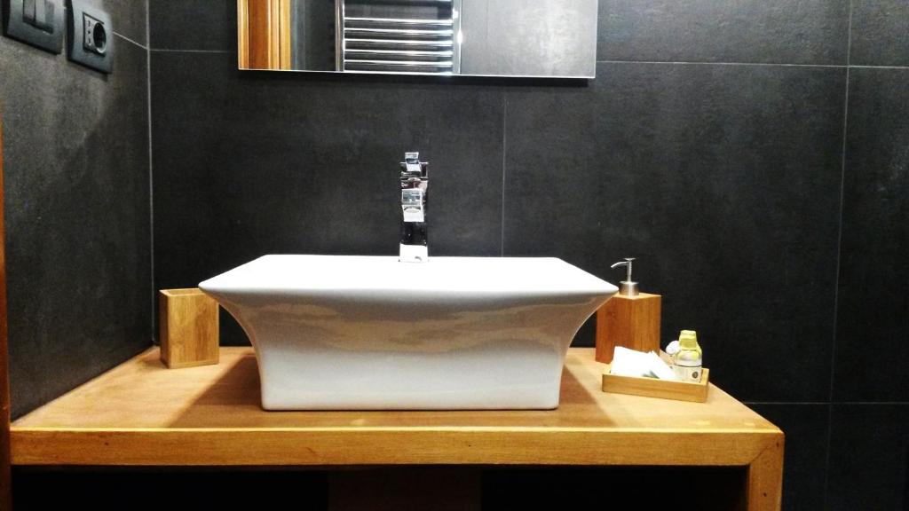 ein Badezimmer mit einem weißen Waschbecken auf einer Holztheke in der Unterkunft LCH-Lateran Charming House in Rom